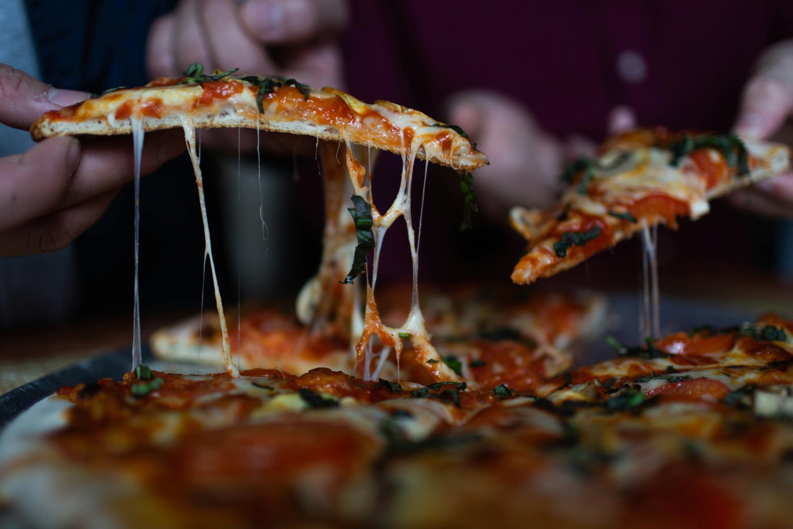 Person pulling a slice of pizza